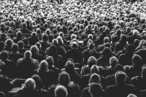 Grote groep theaterbezoekers zit dicht op elkaar in een zaal