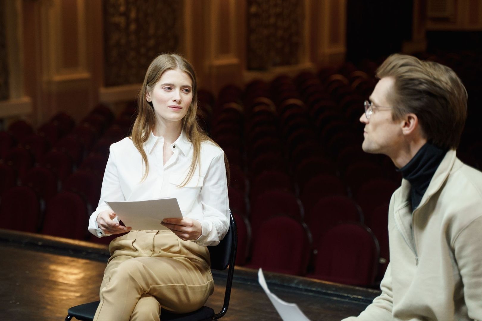 Twee gesprekspartners bespreken een voorstelling in een theaterzaal
